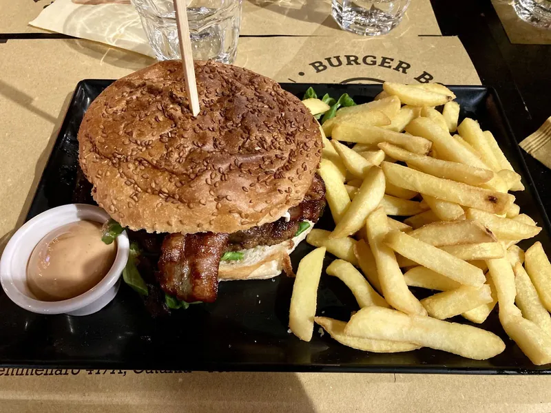 Hamburguesa con bacon y patatas fritas sobre el mantel Burger Boss